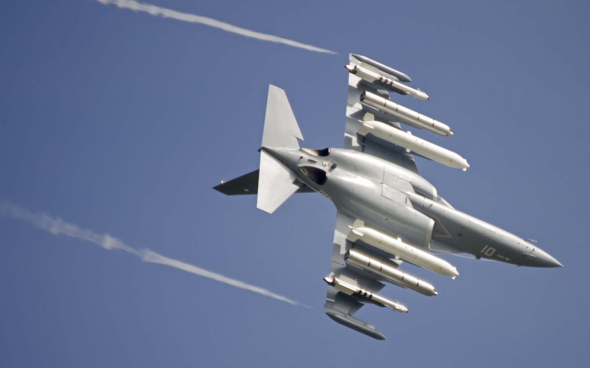 Yakovlev Yak-130 jet fighter warplane in flight with external armaments and vapor trails against a blue sky — military aircraft HD PC desktop wallpaper background.