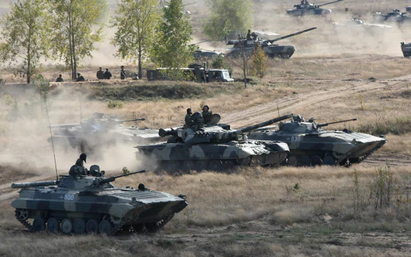 4K Ultra HD PC desktop wallpaper showing an army field exercise with multiple military tanks advancing through a dusty, open terrain surrounded by sparse trees.