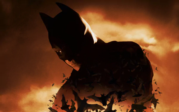 HD desktop wallpaper of Batman Begins, featuring Batman shrouded in darkness with bats flying around, set against a dramatic, fiery sky background.