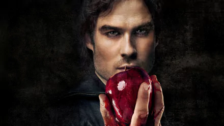 A striking HD wallpaper featuring a character from The Vampire Diaries, holding a blood-red apple, set against a dark background, evoking themes of temptation and danger.