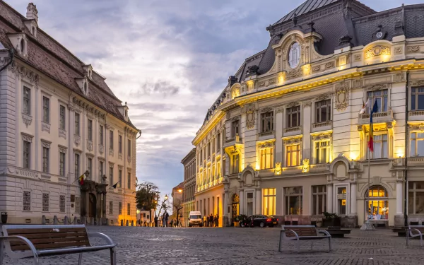 Historic architecture in Sibiu, Transylvania, Romania, showcasing elegant man-made buildings along a city street at dusk in this HD desktop wallpaper and background.