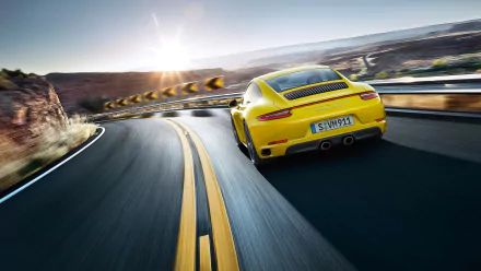 Yellow Porsche 911 Carrera 4S seen from the rear hugging a winding mountain road, captured as a 2K Quad HD PC desktop wallpaper.