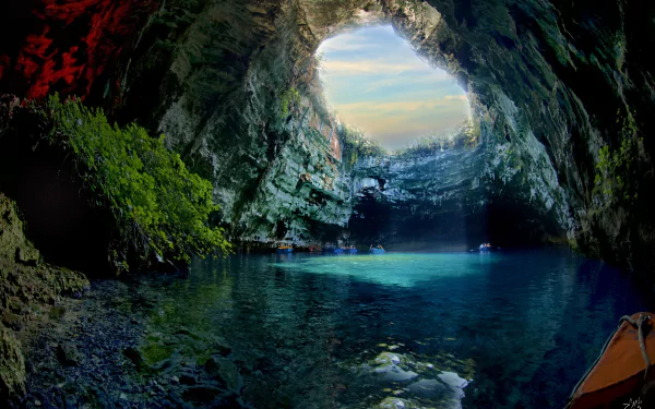 A breathtaking view inside Melissani Cave in Greece, showcasing sunlight streaming through its opening, illuminating the tranquil blue waters and lush greenery.