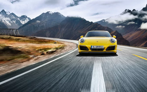 Front view of a yellow Porsche 911 Carrera 4S driving on a winding mountain road, high-resolution 2K Quad HD PC desktop wallpaper background.