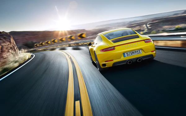 Yellow Porsche 911 Carrera 4S seen from the rear hugging a winding mountain road, captured as a 2K Quad HD PC desktop wallpaper.