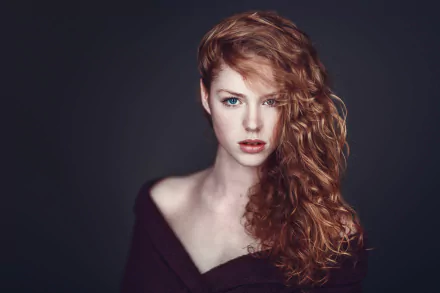 HD desktop wallpaper featuring a redhead female model with curly hair and striking blue eyes against a dark background.