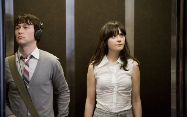 2K desktop wallpaper from the film 500 Days of Summer: two young adults stand in an elevator — a man with headphones and a shoulder bag and a woman in a sleeveless white blouse.