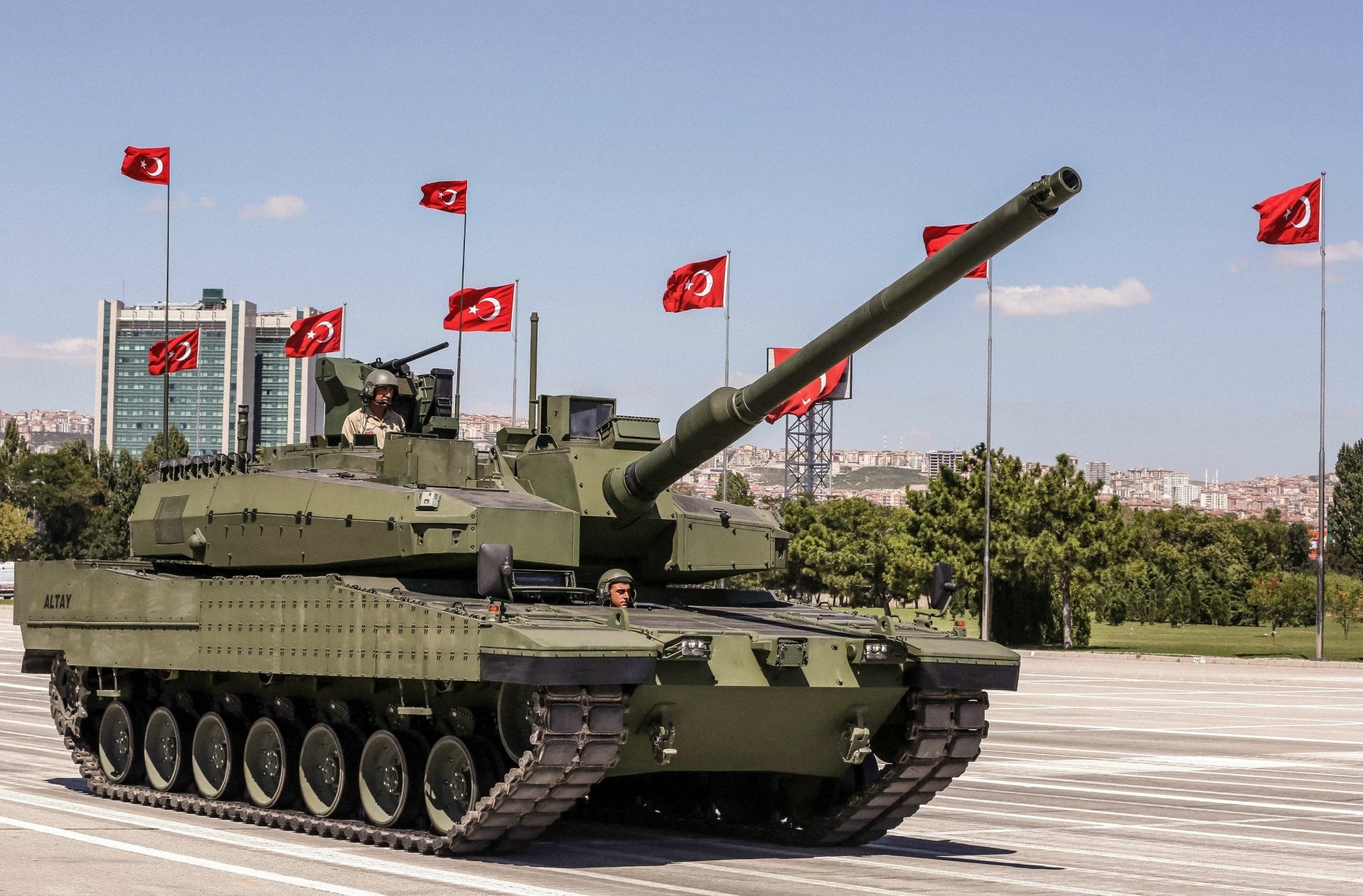 HD desktop wallpaper showcasing an Altay military tank on a paved open area with multiple Turkish flags in the background under a clear sky.