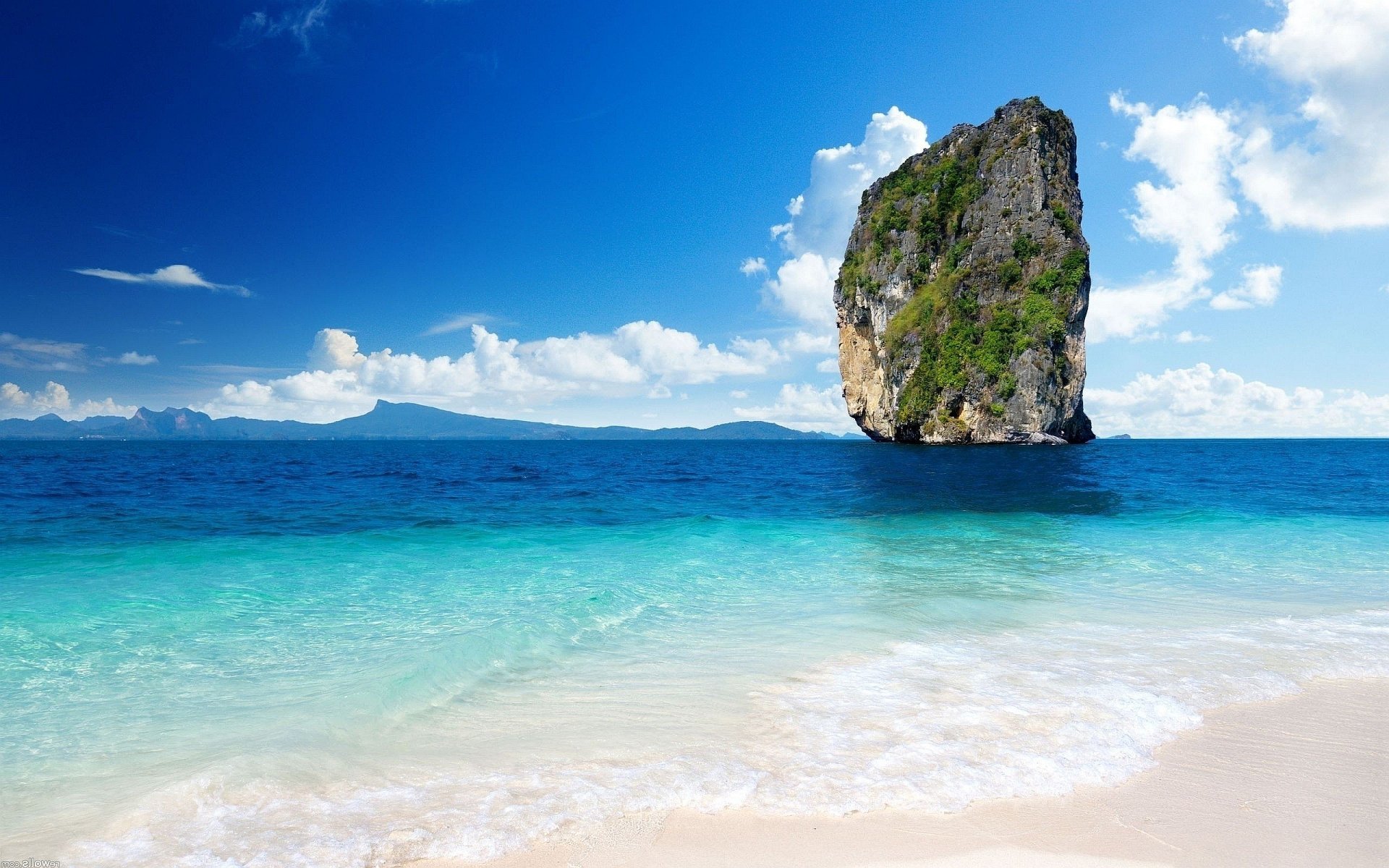 A stunning view of a blue sky over a serene ocean, featuring a rugged cliff off the coast of Thailand, capturing the beauty of nature in vibrant hues.