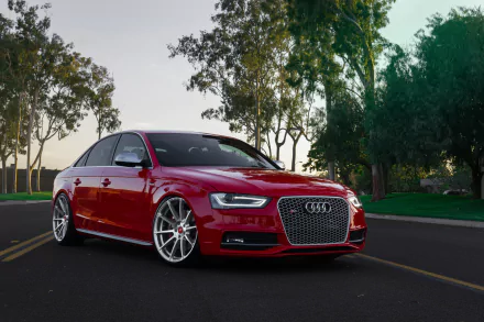 HD desktop wallpaper featuring a red Audi S4 parked on a road, surrounded by trees, showcasing the sleek design of this Audi vehicle.