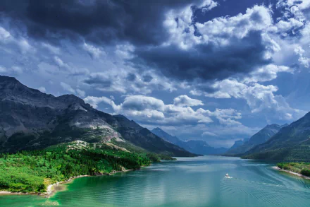 A stunning landscape of Waterton Lakes National Park in Canada, featuring a serene lake surrounded by lush greenery and majestic mountains under a dramatic cloudy sky.
