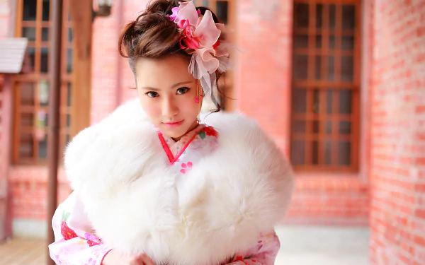 Portrait of a brunette Asian child model with brown eyes, dressed in traditional oriental costume with a fur wrap and floral bow, against a soft bokeh background.