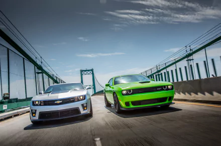 HD PC desktop wallpaper featuring two race cars speeding on a bridge under a partly cloudy sky.