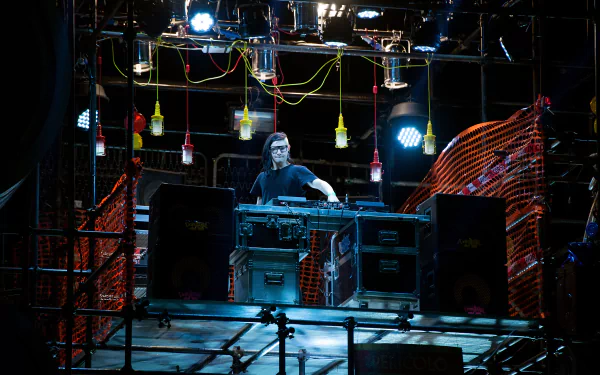 Skrillex performing live with DJ equipment on stage, captured in high detail as a 4K Ultra HD PC desktop wallpaper inspired by Zoolander 2.