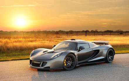 A sleek silver Hennessey Venom GT supercar parked on a road at sunset, surrounded by golden fields, making an impressive HD desktop wallpaper.