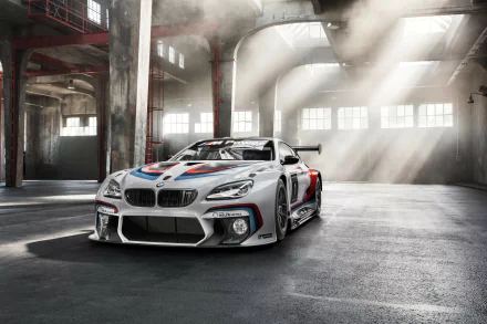 HD desktop wallpaper featuring a BMW M6 GT3 race car in a spacious industrial setting with light rays highlighting the vehicle's detailed design and racing livery.