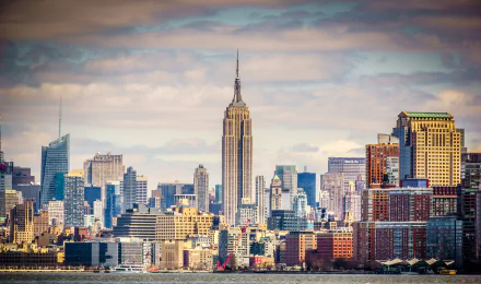 HD desktop wallpaper of the New York City skyline featuring the iconic Empire State Building under a partly cloudy sky in the USA.