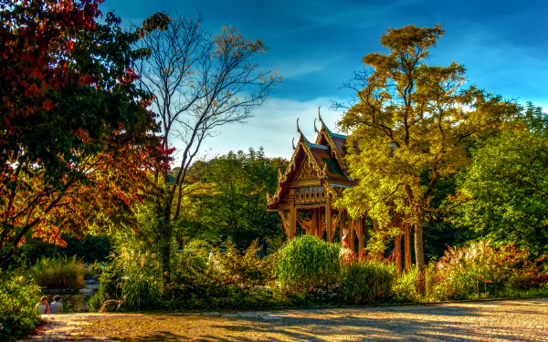 A serene park in Germany featuring a man-made religious pagoda surrounded by trees under a vivid blue sky, captured in HD for a desktop wallpaper background.