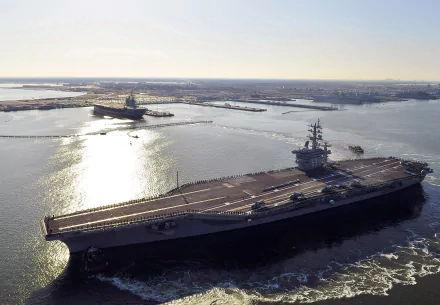 Aerial view of the USS Dwight D. Eisenhower (CVN-69) aircraft carrier at sea, showcasing the warship and navy operations in clear daylight.