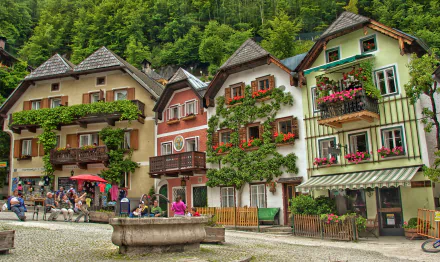 Charming houses adorned with flowers line the streets of Hallstatt, Austria, showcasing the town's picturesque man-made beauty against a lush green backdrop.