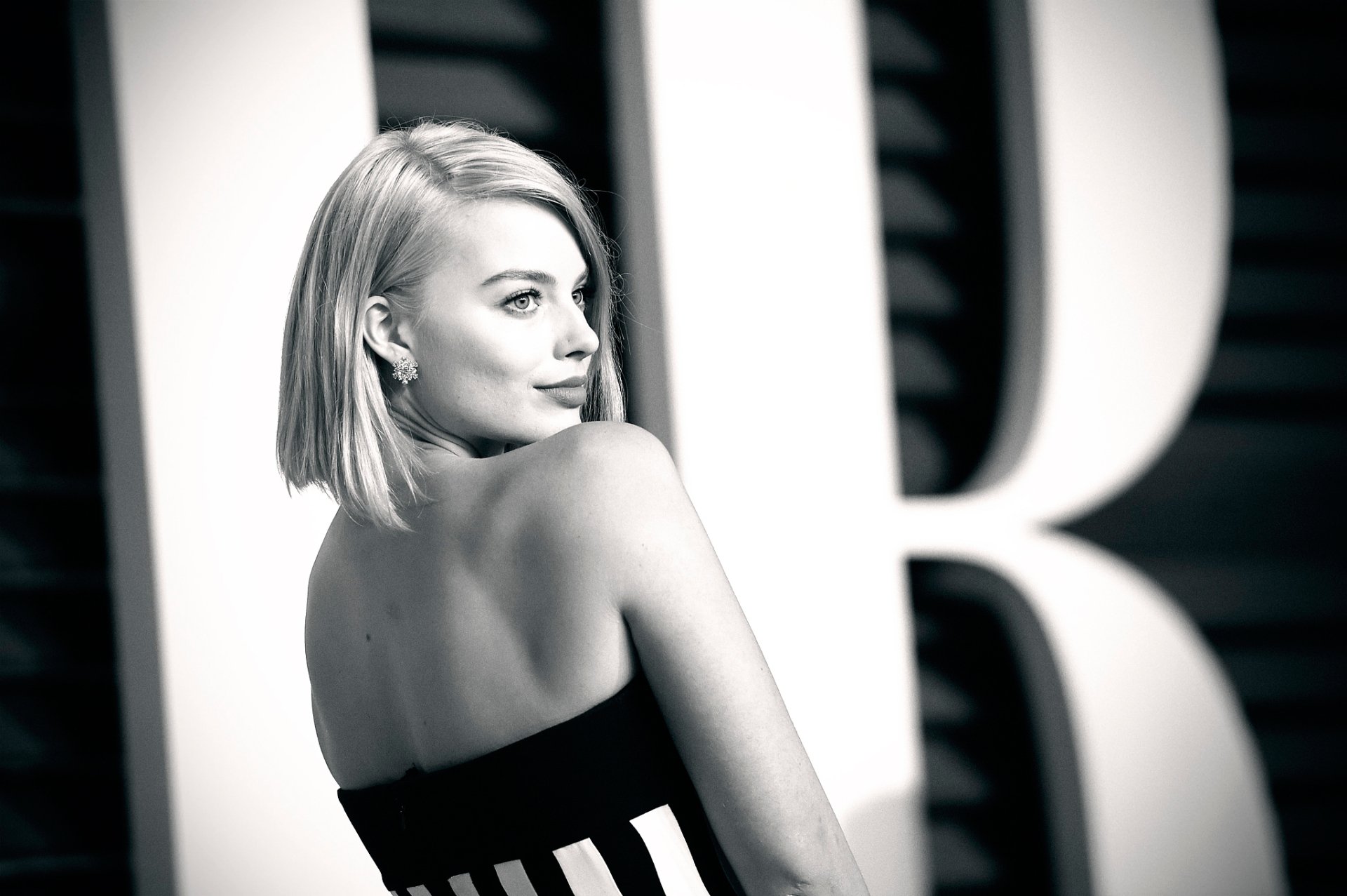 A black and white HD wallpaper featuring Australian actress Margot Robbie, showcasing her elegant profile against a prominent backdrop.