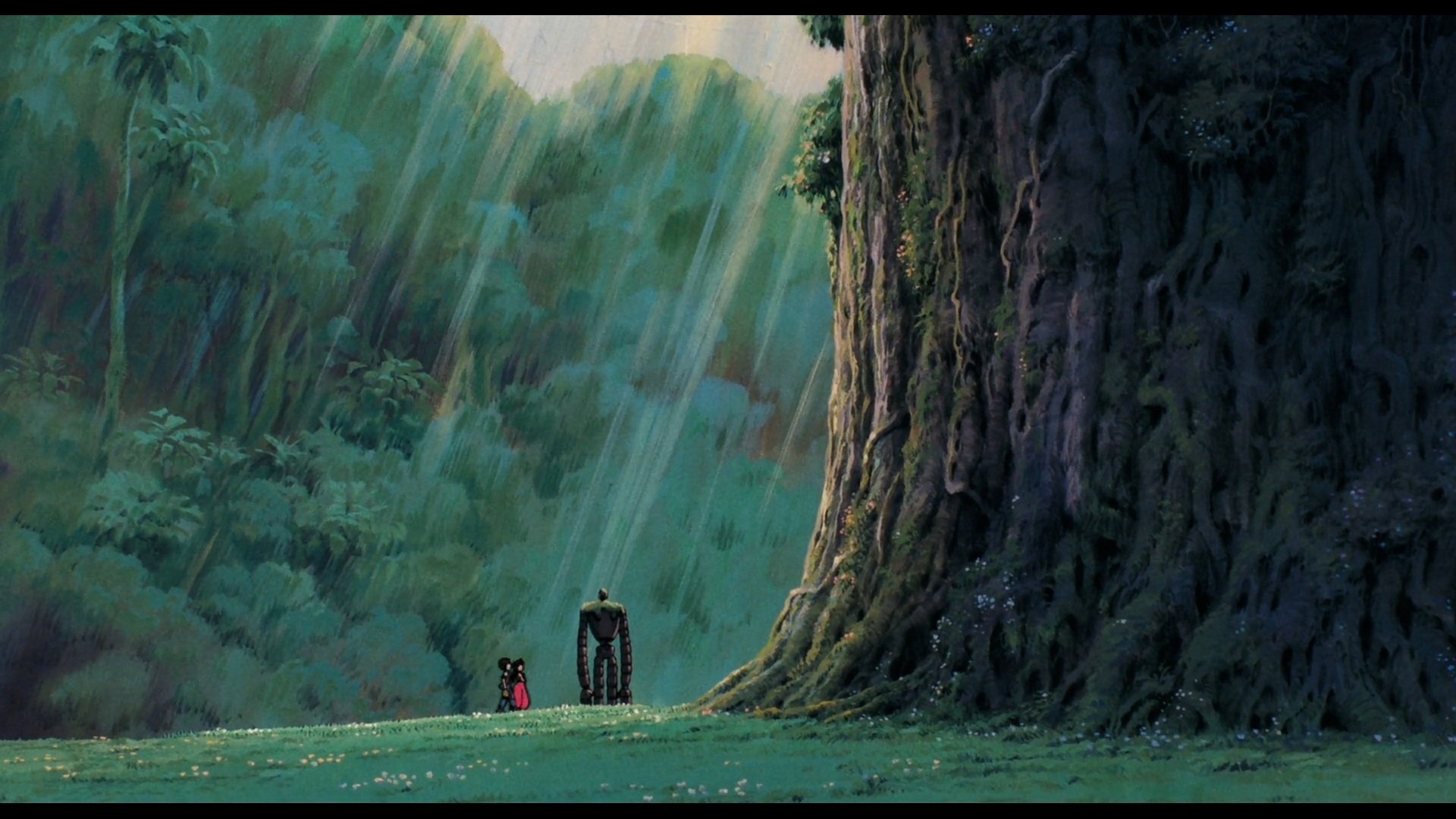 HD PC desktop wallpaper from the anime Laputa: Castle in the Sky, featuring a lush forest scene with two small figures standing near a massive tree bathed in sunlight.