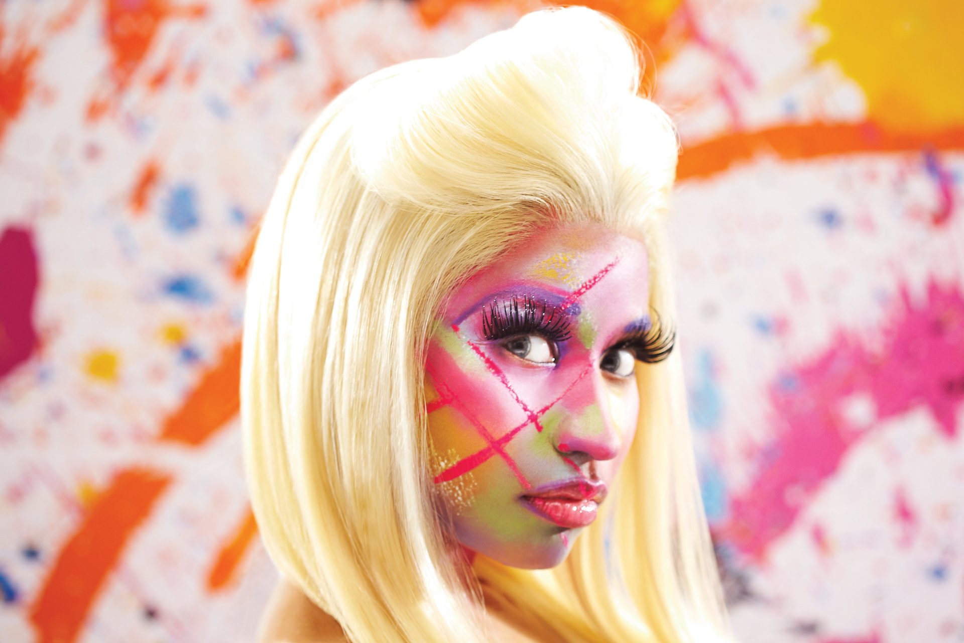 HD desktop wallpaper featuring a colorful portrait of a person with vibrant face paint, reminiscent of Nicki Minaj, against a splattered paint backdrop.