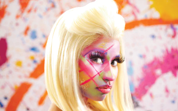 HD desktop wallpaper featuring a colorful portrait of a person with vibrant face paint, reminiscent of Nicki Minaj, against a splattered paint backdrop.