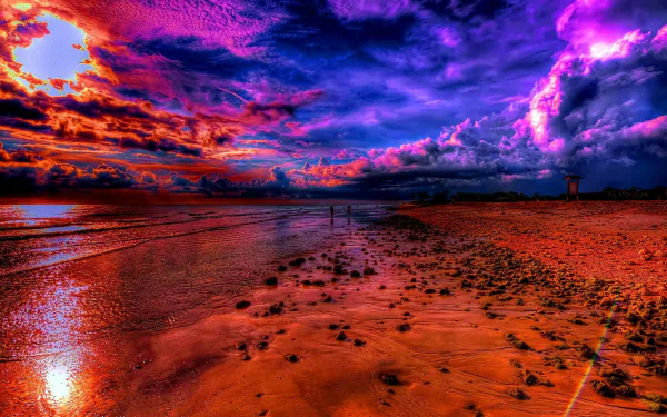 Vivid HDR photograph of a sunset over an ocean horizon, depicting a colorful sky and a beach dotted with rocks. HD desktop wallpaper and background.