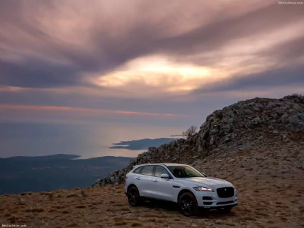 Jaguar F-PACE SUV parked on rocky terrain under a dramatic sky, captured in an HD desktop wallpaper showcasing the elegant design of the Jaguar vehicle.