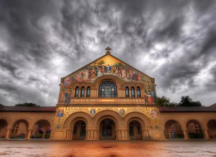 HD desktop wallpaper featuring the ornate arch and vibrant mural of Stanford Church under a dramatic cloudy sky, showcasing its religious architecture.
