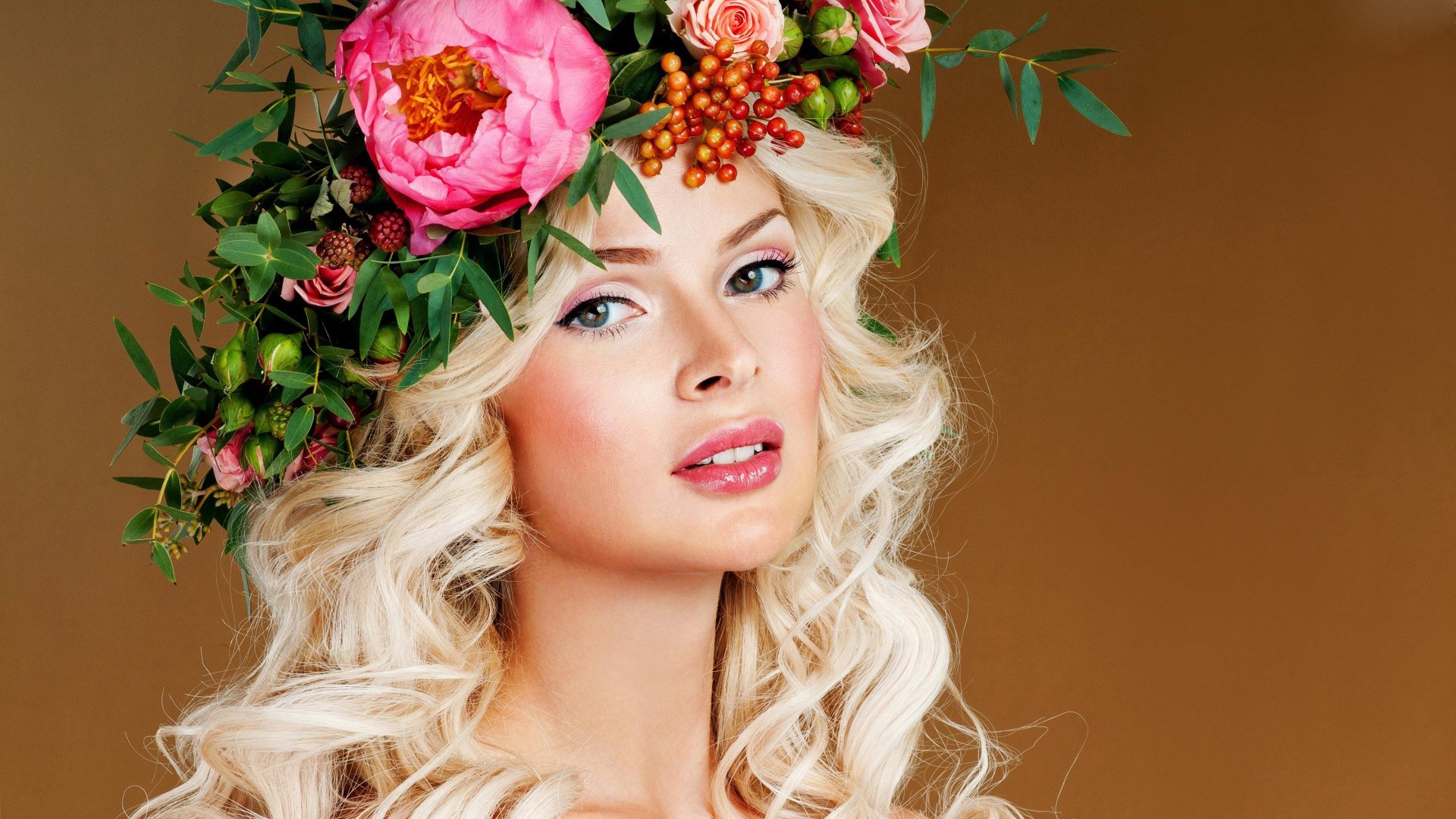 A blonde woman with blue eyes showcases a radiant expression, adorned with a vibrant flower wreath, set against a warm background. 4K Ultra HD wallpaper quality.