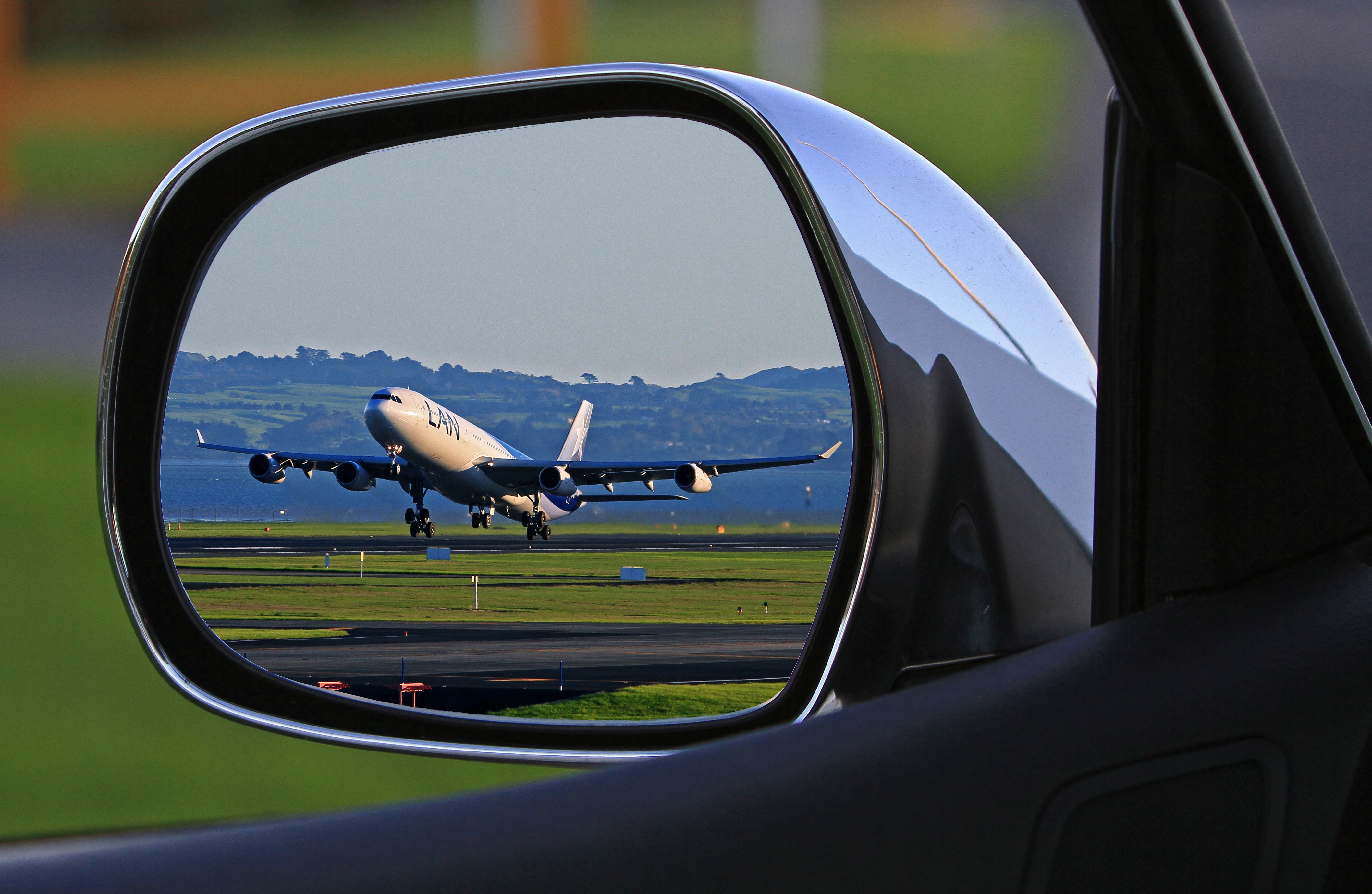 An lan airbus a320 in the side view mirror of a car by Holgi