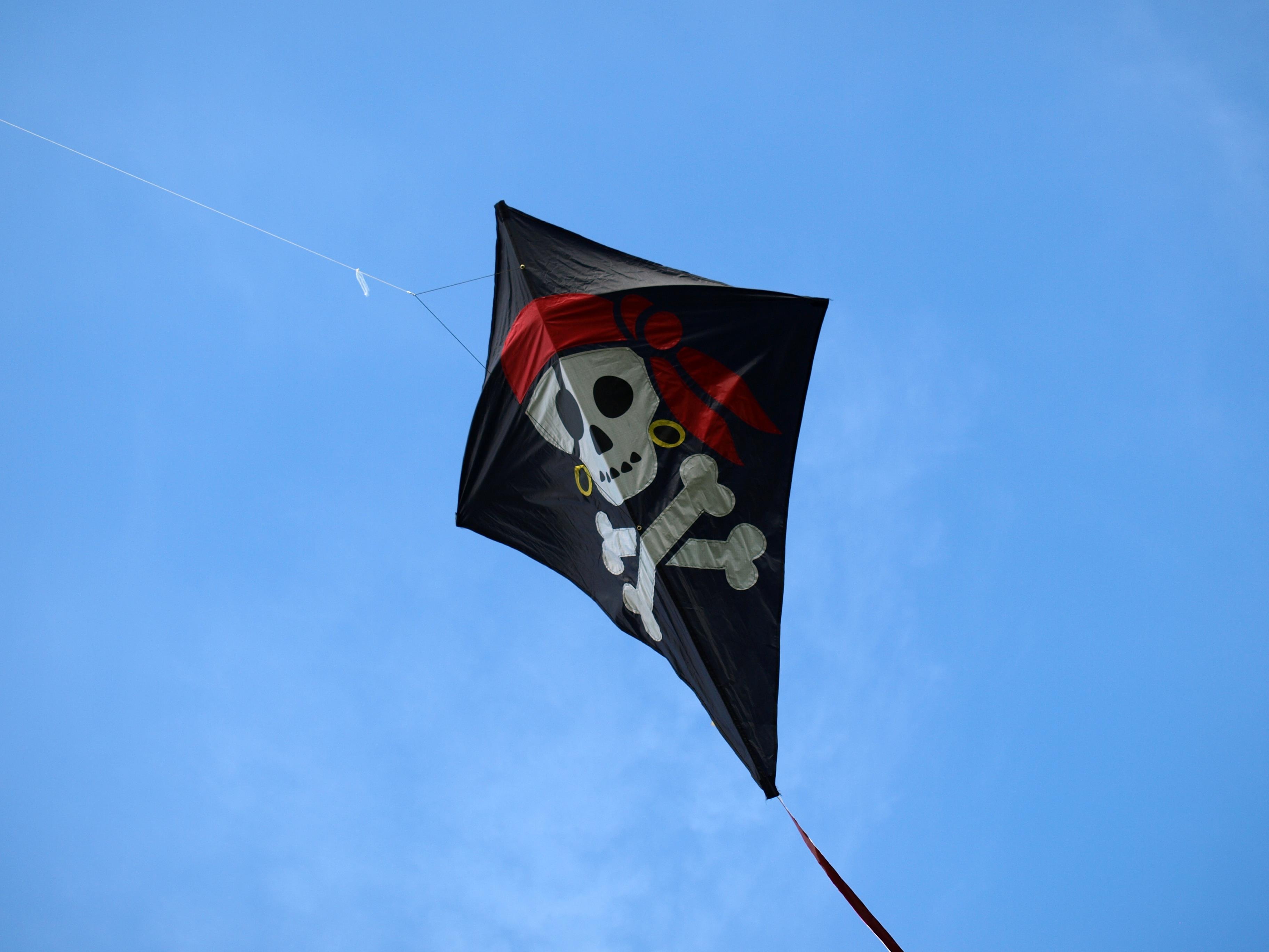 The jolly roger skull and crossbones pirate kite flying in the sky by ariesa66