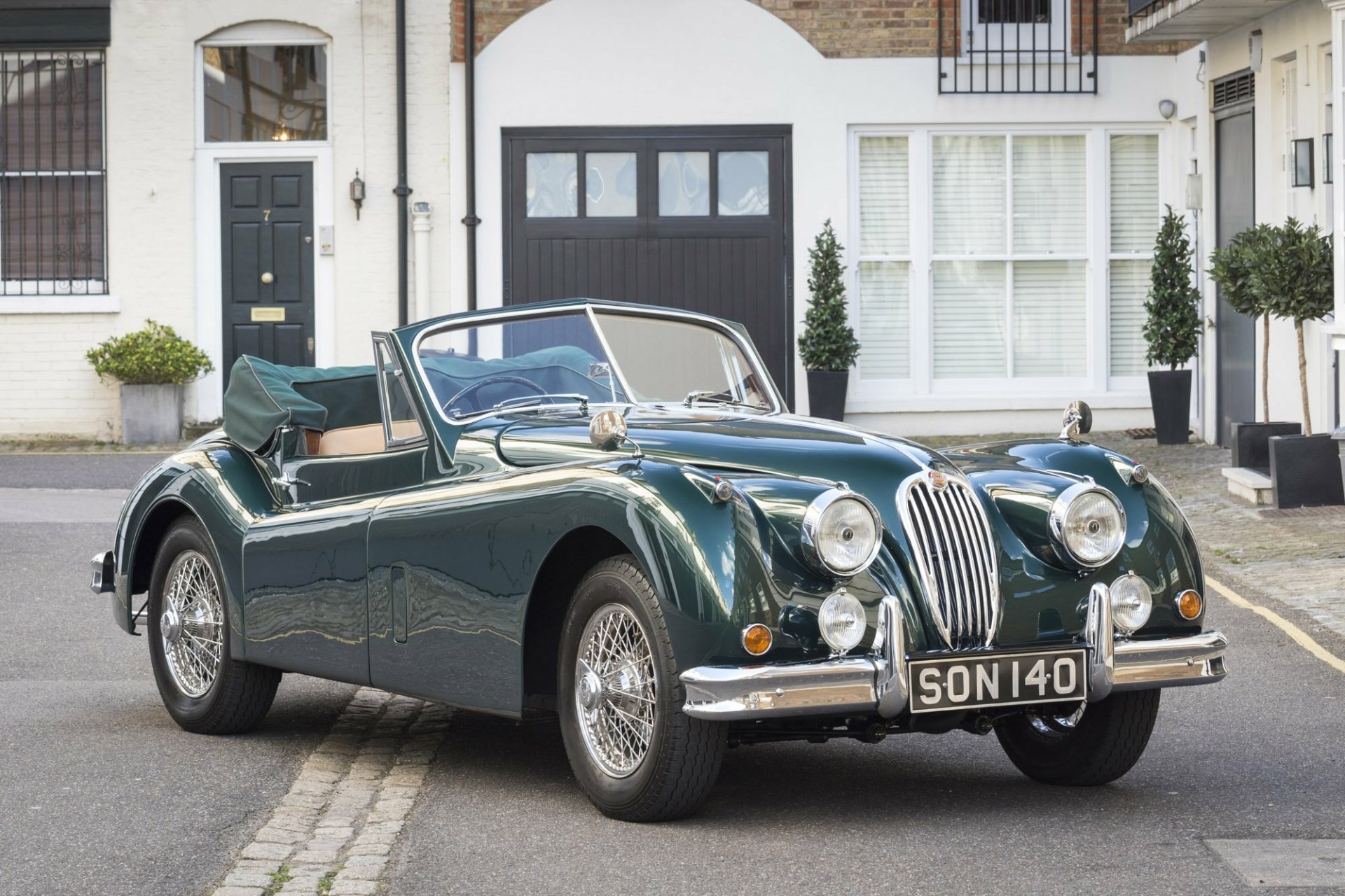 HD PC desktop wallpaper featuring a classic Jaguar XK140 convertible parked on a quiet residential street.