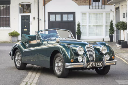HD PC desktop wallpaper featuring a classic Jaguar XK140 convertible parked on a quiet residential street.