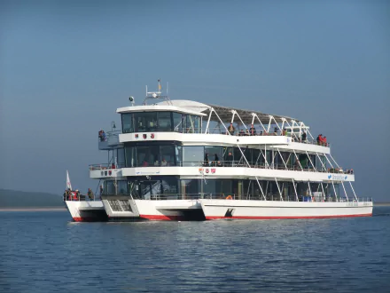A passenger ferry carrying people glides calmly across clear blue water, captured in stunning 4K Ultra HD as a desktop wallpaper and background.