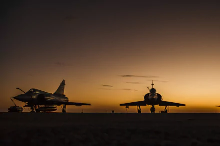 Silhouette of Dassault Mirage 2000 jet fighters against a vibrant sunset. This HD image captures the essence of military aviation in a stunning background.