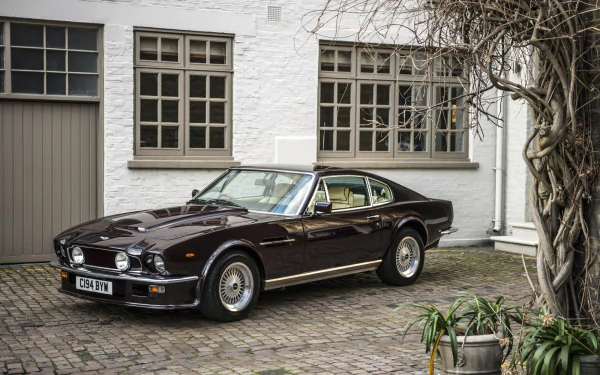 A sleek Aston Martin Vantage parked in a stylish courtyard, showcasing its classic design. This HD image serves as a stunning desktop wallpaper and background.