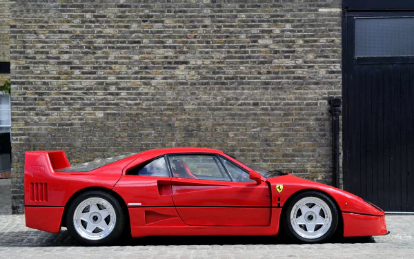 HD PC desktop wallpaper featuring a red Ferrari F40 parked beside a brick wall, showcasing the iconic vehicle's sleek and classic design.