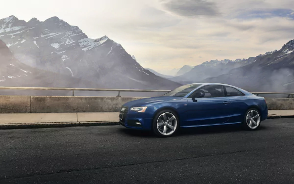 HD PC desktop wallpaper of a blue Audi A5 coupe parked on a mountain overlook, dramatic misty peaks and cloudy sky behind the vehicle