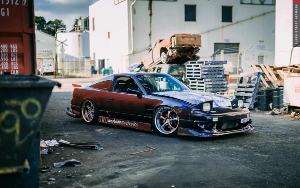 HD PC desktop wallpaper featuring a Nissan 180SX parked in an industrial setting, showcasing its sleek design and modified exterior.