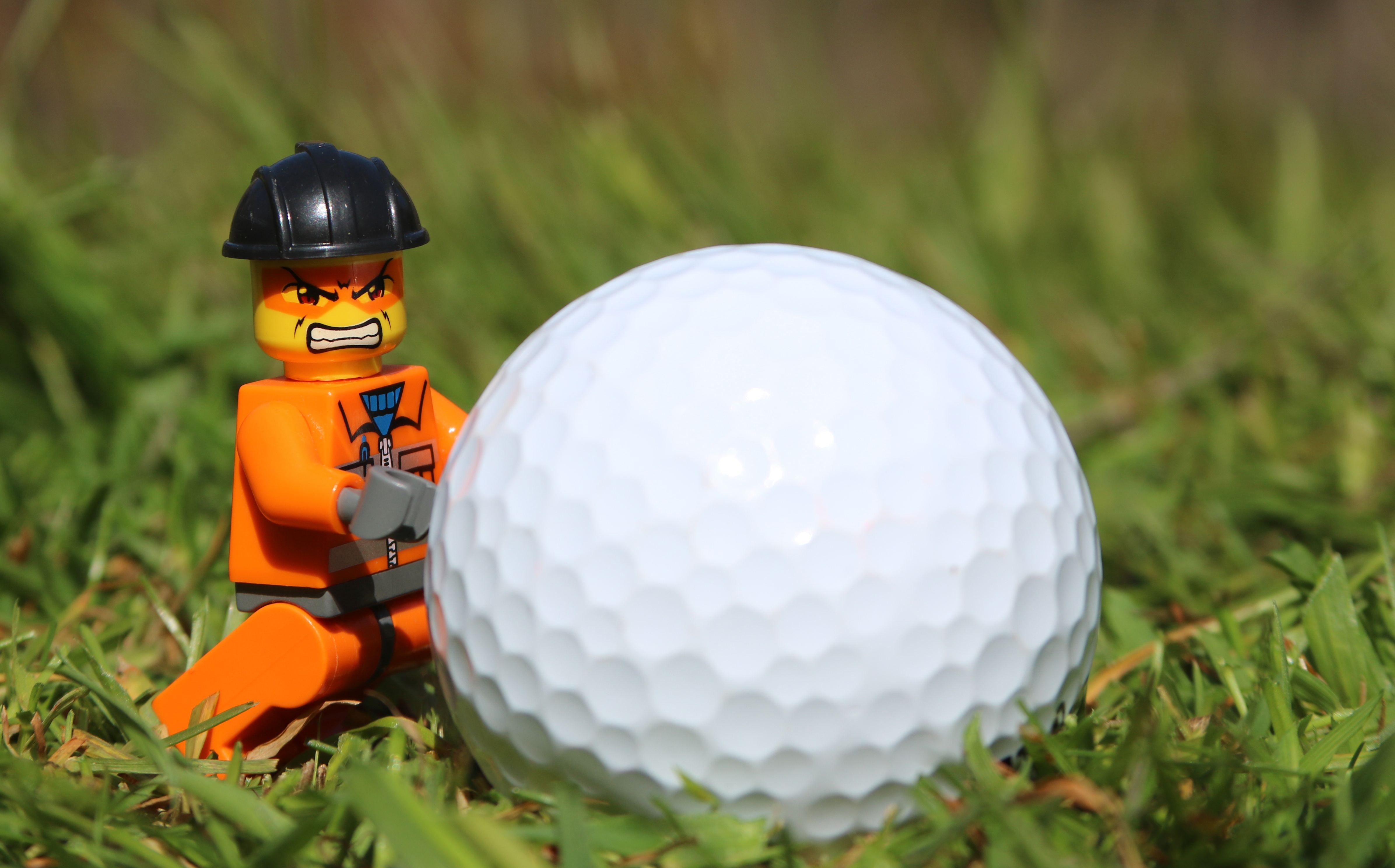 Lego construction worker trying to move a golf ball by jlaswilson