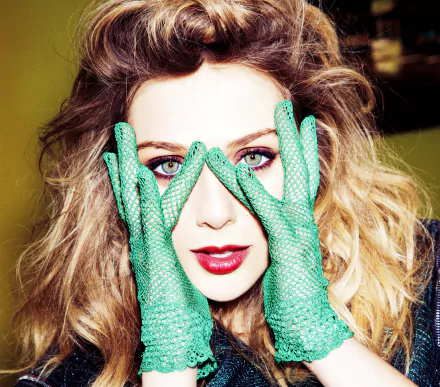 Elizabeth Olsen poses with striking green gloves, framing her face, showcasing her vibrant eyes and bold makeup in this high-definition desktop wallpaper and background.
