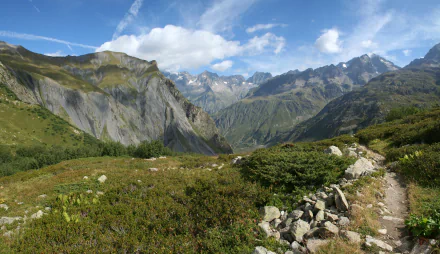 HD desktop wallpaper showcasing a breathtaking landscape of the Alps with towering mountains, a lush valley, and vibrant natural greenery under a bright blue sky.