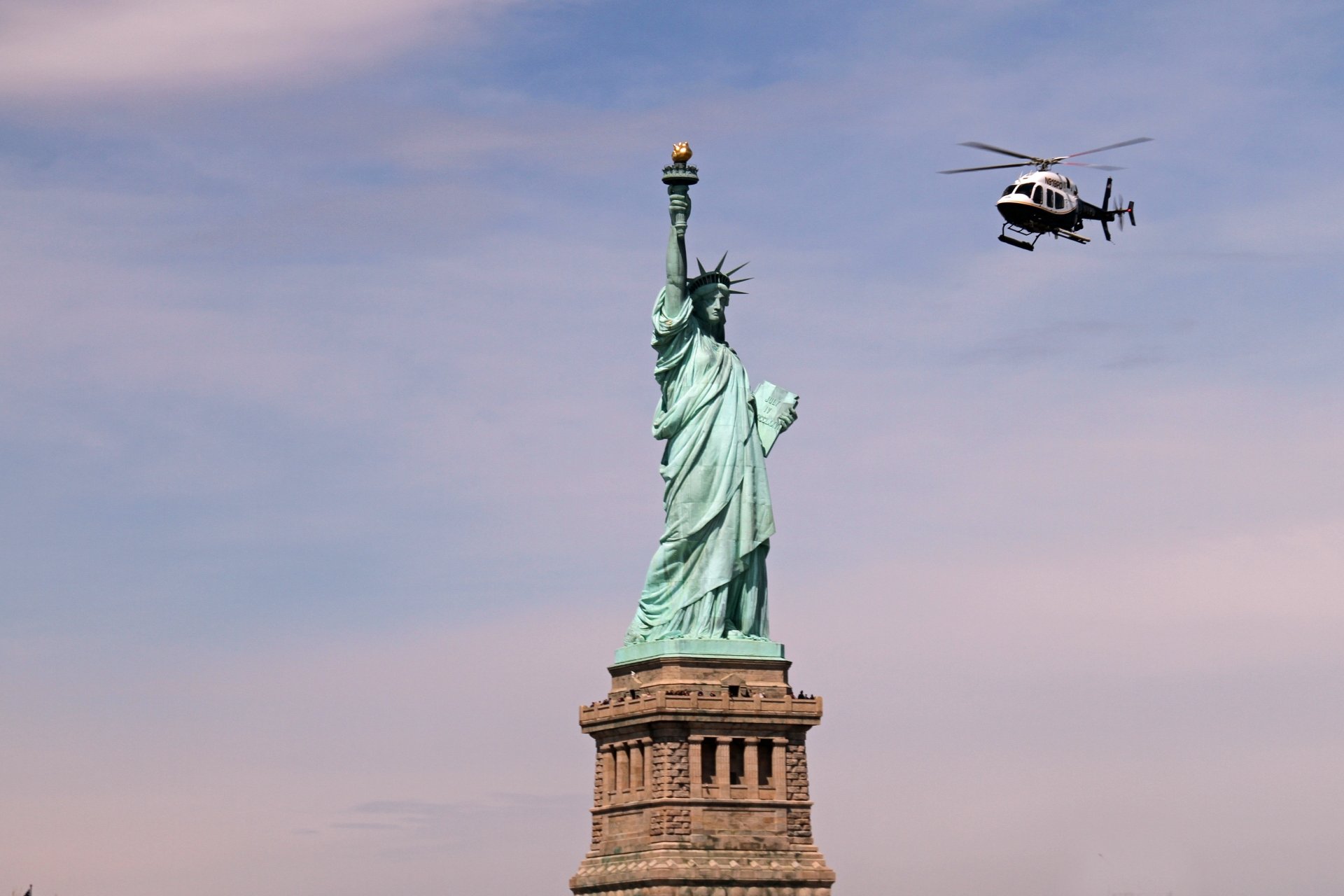 Statue of Liberty under a pastel sky with a helicopter hovering nearby in New York, USA — 5K Ultra HD PC desktop wallpaper of the iconic man-made monument.