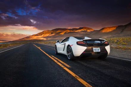 White McLaren MP4-12C Spider supercar drives on an open road at sunset, set against a scenic mountainous desert landscape in this HD desktop wallpaper.
