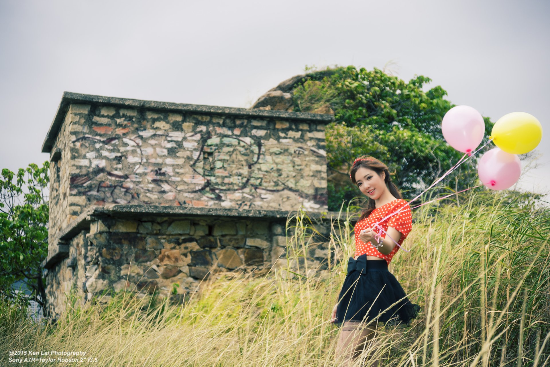 A woman, tagged Wing Wing, stands in front of an old stone building holding balloons. The image serves as an HD desktop wallpaper and background.
