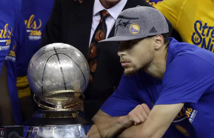 A close-up of a Golden State Warriors player gazing at a championship trophy, capturing a moment of triumph in sports. HD wallpaper background celebrating their success.