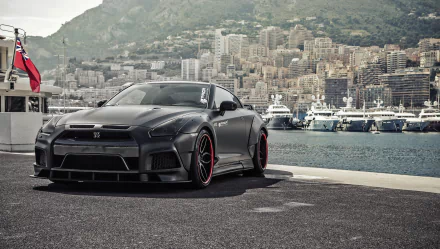 A sleek silver Nissan GT-R parked along a scenic waterfront, showcasing its dynamic design against a backdrop of luxurious yachts and a mountainous cityscape.